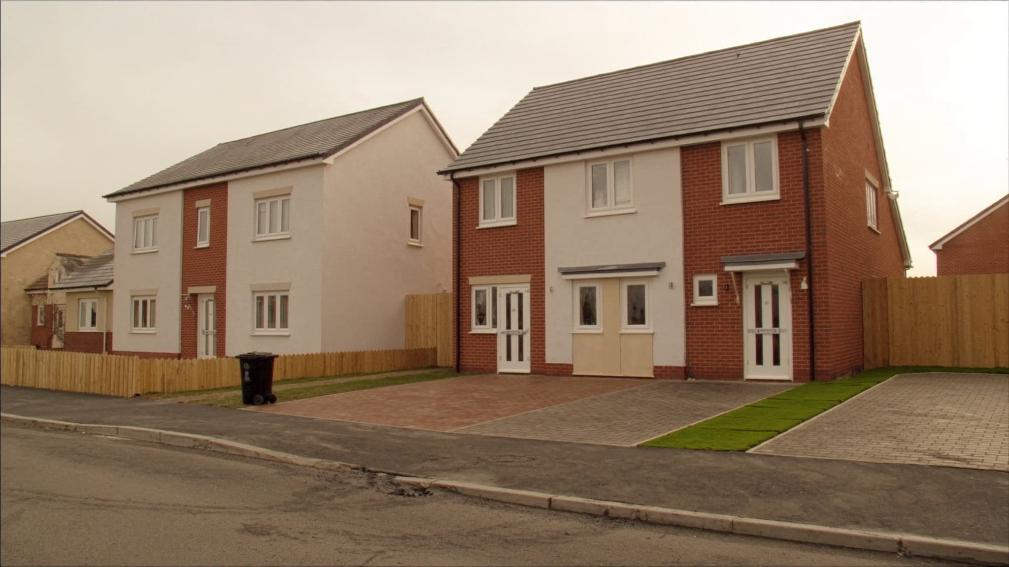 Newly finished British new build houses in brick and render behind fresh block paving